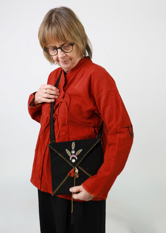 Woman in a red shirt holding a black handbag with decorative elements on a white background
