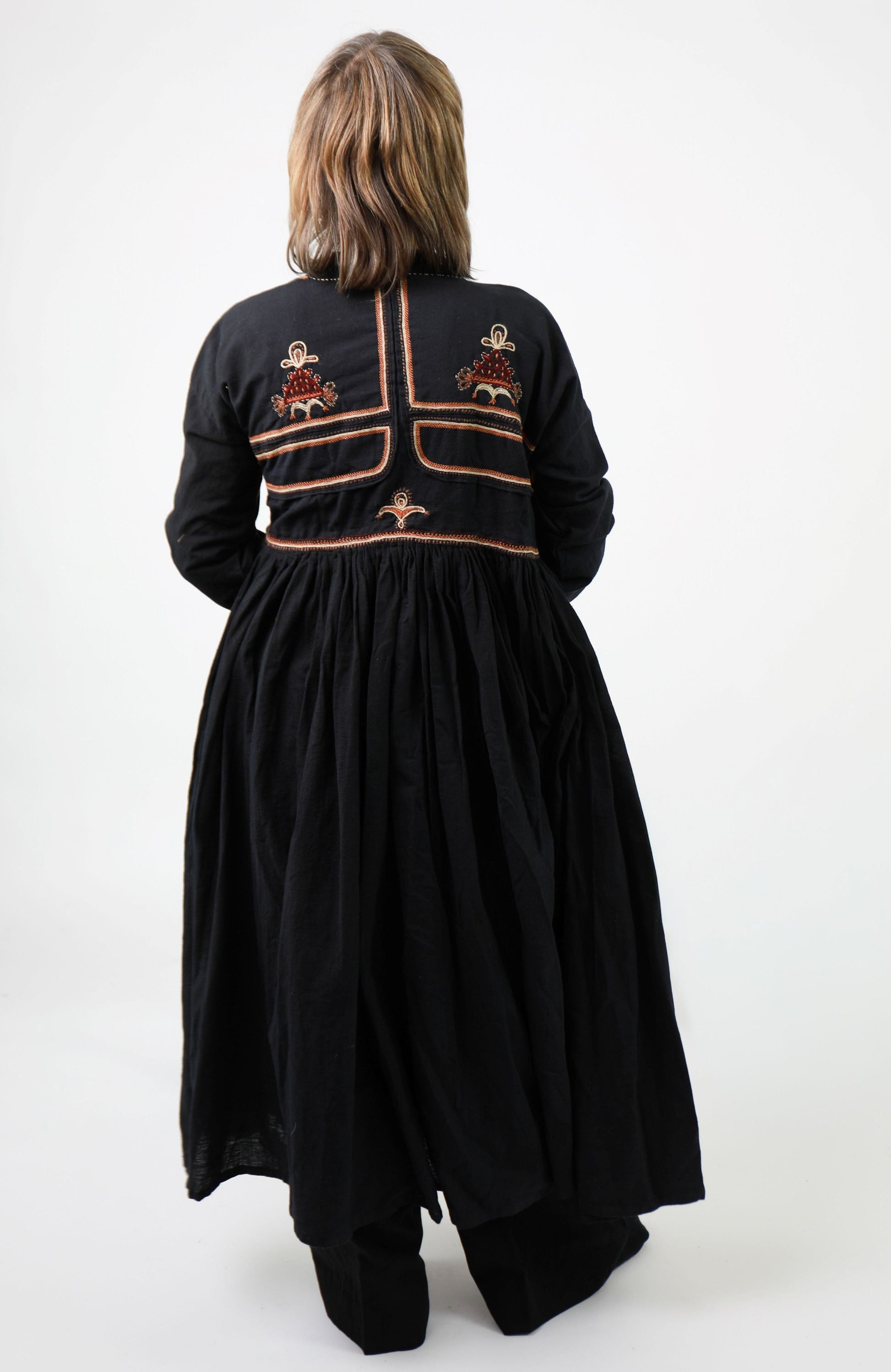 Person wearing a black embroidered dress on a white background