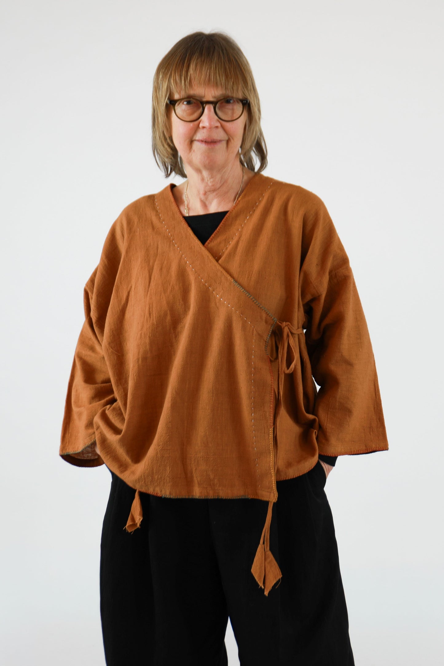Person wearing a brown top with black pants on a white background