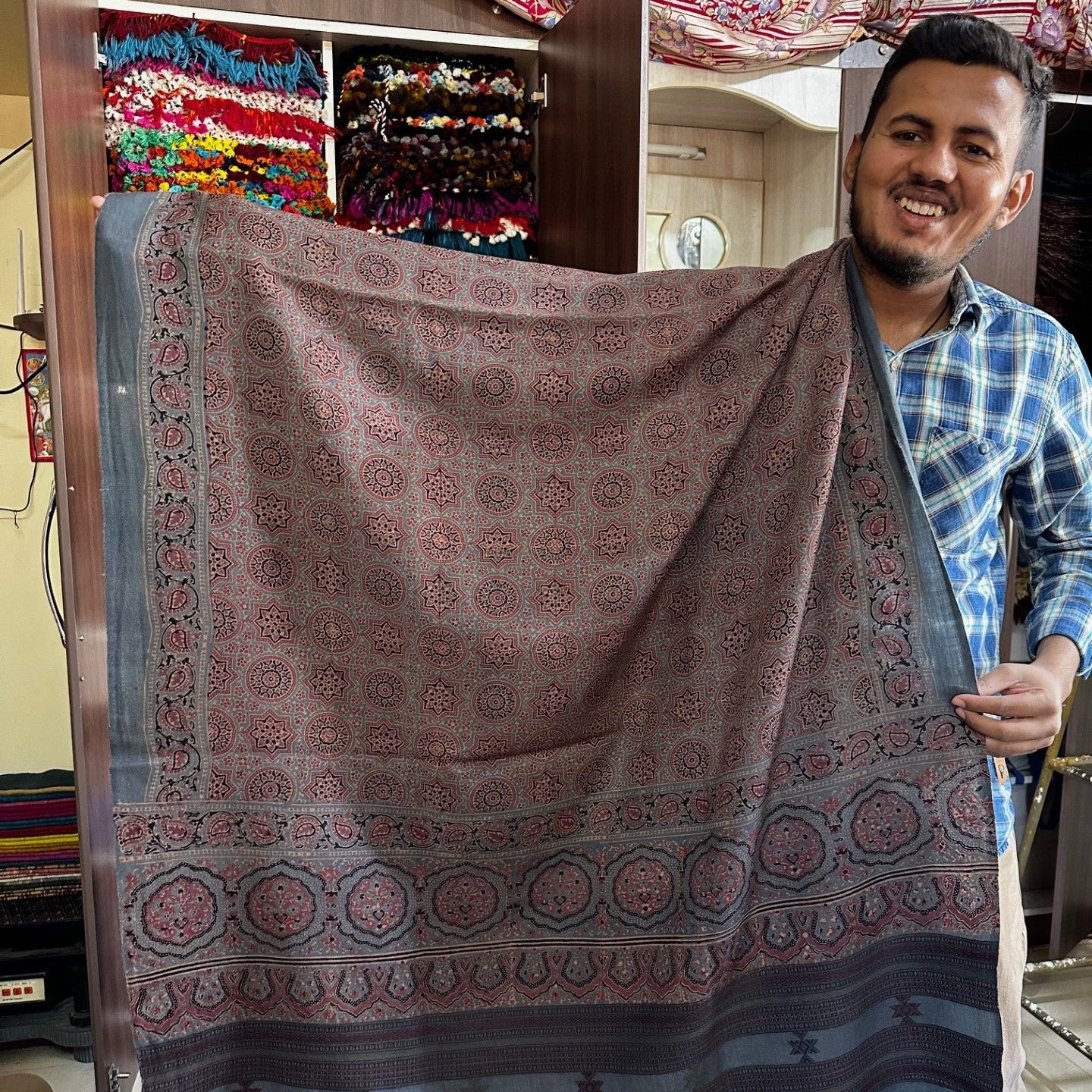 Man holding a patterned fabric in front of a colorful background